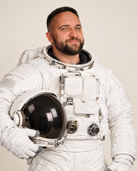 Deividas Iršas in a spacesuit, helmet under his arm